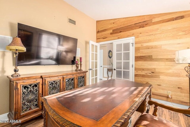 office space with french doors, lofted ceiling, and wood walls