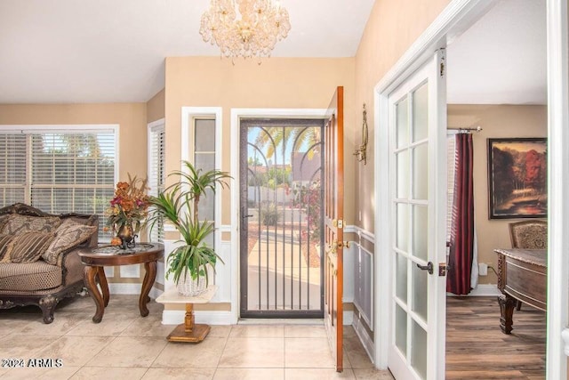 entryway with a chandelier, light tile patterned floors, and french doors