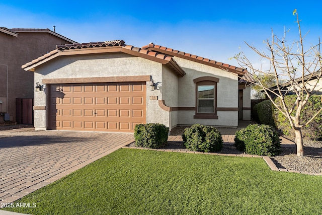 view of front of property featuring an attached garage, a tile roof, decorative driveway, stucco siding, and a front yard