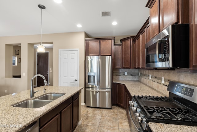 kitchen with a sink, visible vents, appliances with stainless steel finishes, light stone countertops, and tasteful backsplash