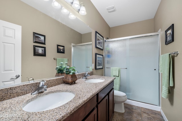 bathroom with double vanity, a sink, toilet, and a shower stall