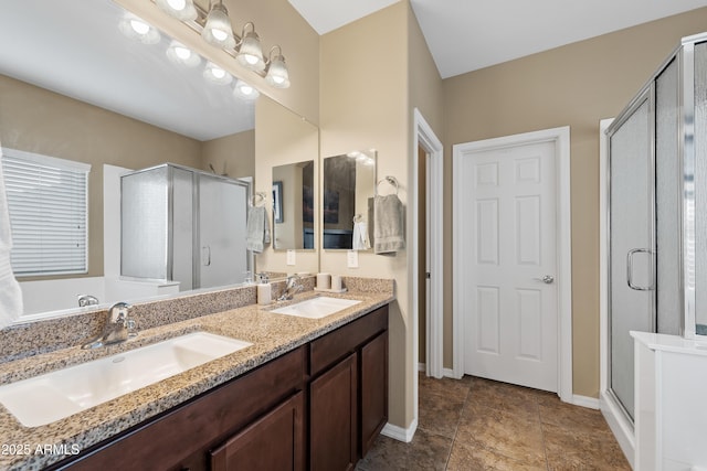 bathroom with double vanity, a stall shower, and a sink