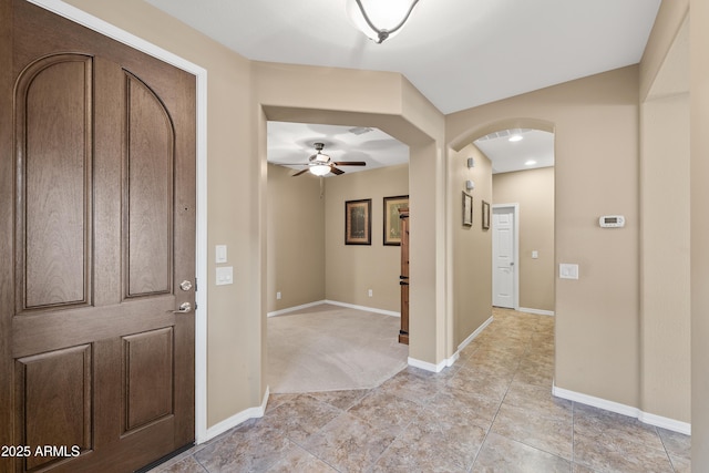 entrance foyer featuring arched walkways, ceiling fan, and baseboards