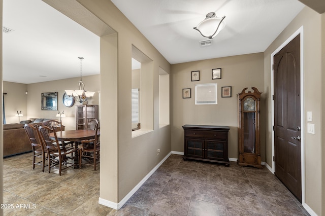 foyer featuring baseboards, visible vents, and a notable chandelier