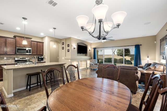 dining room with ceiling fan with notable chandelier, baseboards, visible vents, and recessed lighting