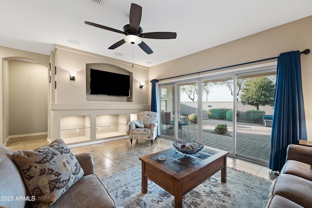 living area featuring arched walkways, ceiling fan, and light tile patterned floors