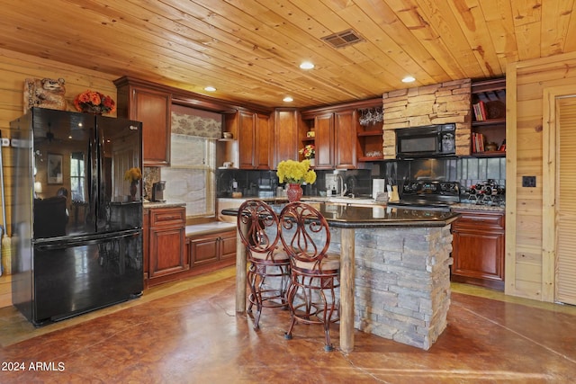 kitchen featuring black appliances, a kitchen bar, a kitchen island, and wooden walls