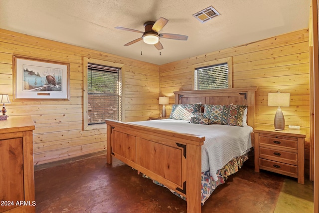 bedroom with ceiling fan, a textured ceiling, and wood walls