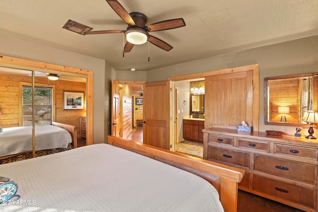 bedroom with connected bathroom, ceiling fan, a textured ceiling, and wood walls