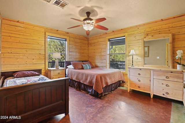 bedroom featuring multiple windows, wood walls, and ceiling fan