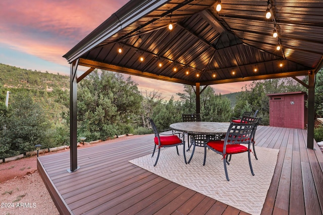 deck at dusk featuring a gazebo