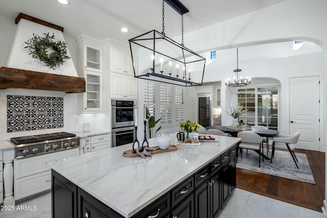 kitchen with a kitchen island, pendant lighting, tasteful backsplash, white cabinetry, and stainless steel appliances