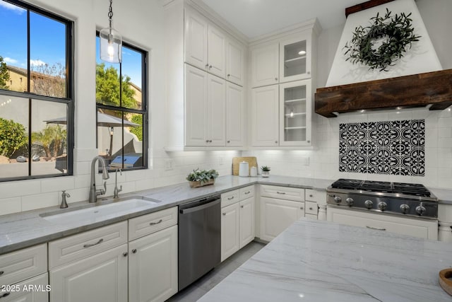 kitchen featuring appliances with stainless steel finishes, decorative light fixtures, sink, white cabinets, and custom exhaust hood