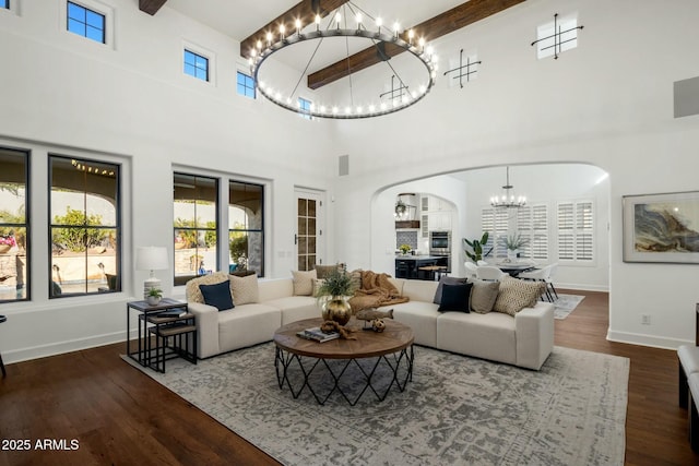 living room with a notable chandelier, a towering ceiling, dark hardwood / wood-style floors, and beamed ceiling