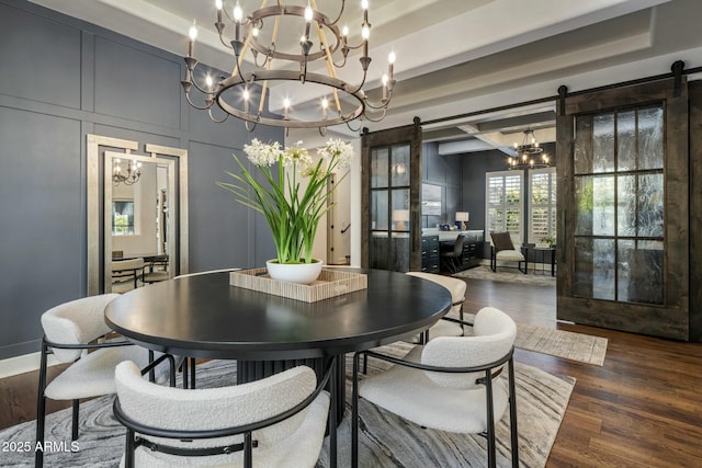 dining room featuring a barn door, dark wood-type flooring, a notable chandelier, and a tray ceiling