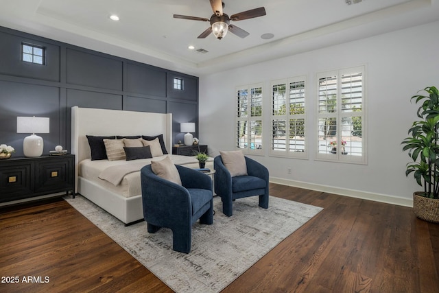 bedroom featuring ceiling fan, wood-type flooring, and a tray ceiling