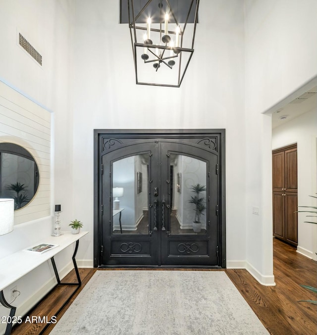 entrance foyer with a notable chandelier, a towering ceiling, and dark hardwood / wood-style floors