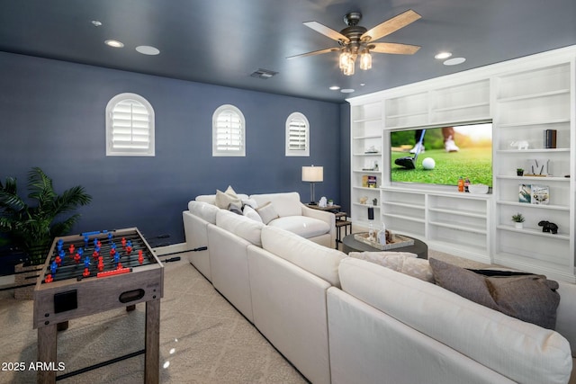 carpeted living room with built in shelves and ceiling fan