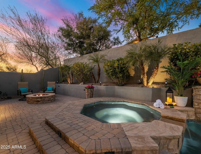 pool at dusk with an in ground hot tub, a patio, and a fire pit