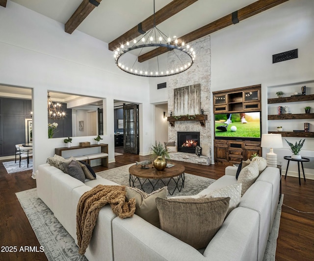 living room featuring a fireplace, dark hardwood / wood-style floors, a notable chandelier, a towering ceiling, and beam ceiling