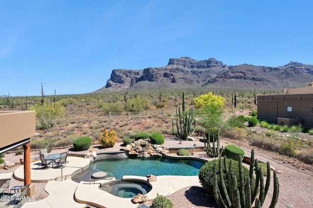 view of swimming pool featuring fence, a mountain view, a pool with connected hot tub, and a patio
