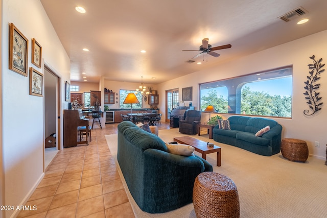 tiled living room with ceiling fan with notable chandelier