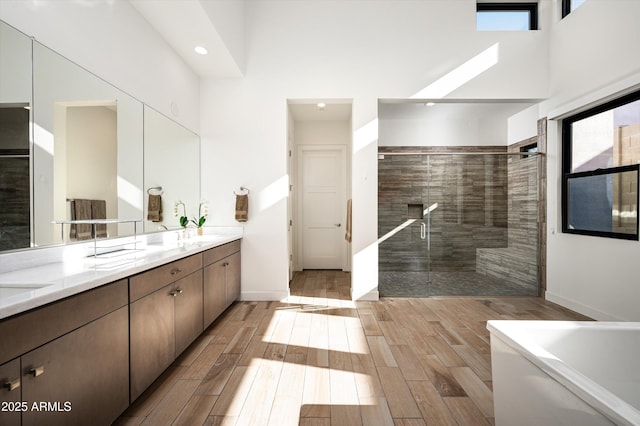 bathroom featuring independent shower and bath, vanity, a high ceiling, and a healthy amount of sunlight