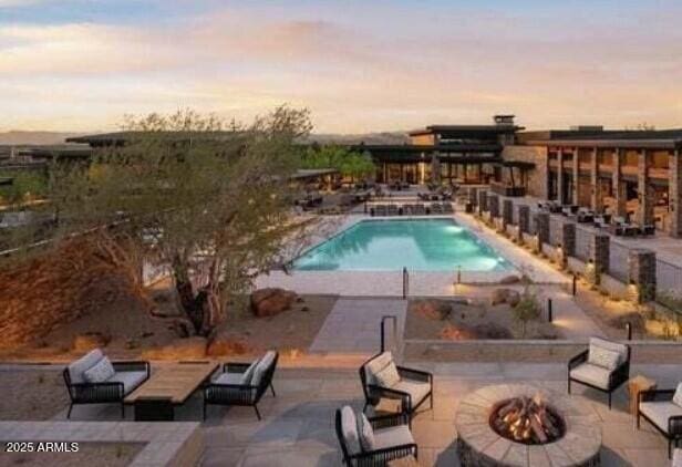 pool at dusk featuring a patio area and an outdoor fire pit