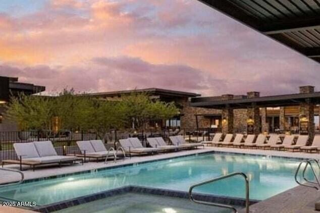 pool at dusk featuring a community hot tub