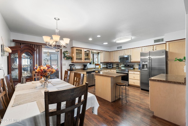 kitchen featuring stainless steel appliances, a center island, visible vents, and dark wood-type flooring