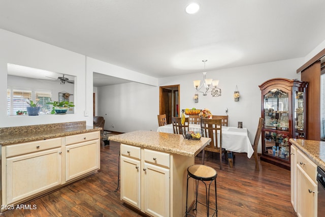 kitchen featuring a breakfast bar, pendant lighting, a center island, dark wood-type flooring, and ceiling fan with notable chandelier