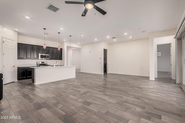 kitchen featuring a kitchen island with sink, decorative light fixtures, ceiling fan, wood-type flooring, and appliances with stainless steel finishes