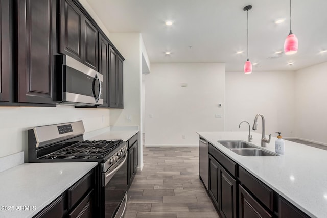 kitchen with dark hardwood / wood-style flooring, decorative light fixtures, light stone countertops, sink, and appliances with stainless steel finishes