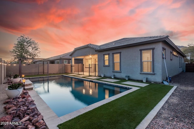 pool at dusk featuring a pergola and a lawn