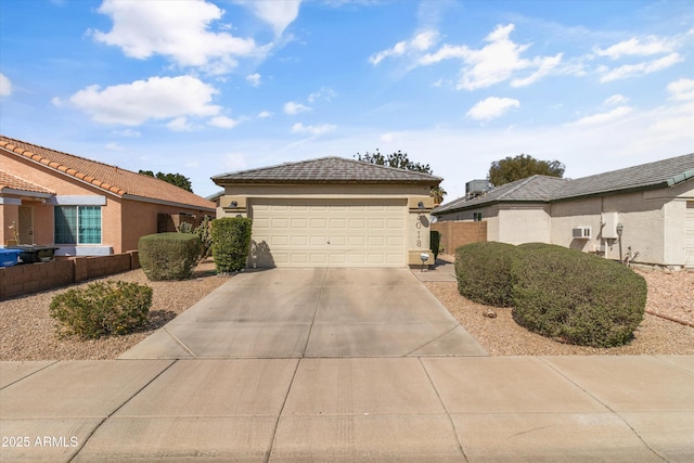 view of front of house featuring fence, a tiled roof, stucco siding, a garage, and driveway