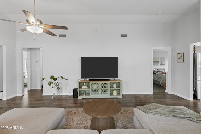 living room featuring visible vents, a ceiling fan, baseboards, and wood finished floors