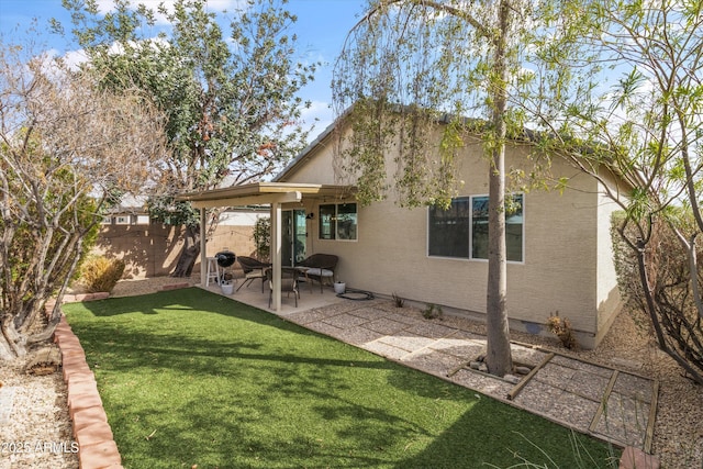 back of house with a yard, a patio area, a fenced backyard, and stucco siding