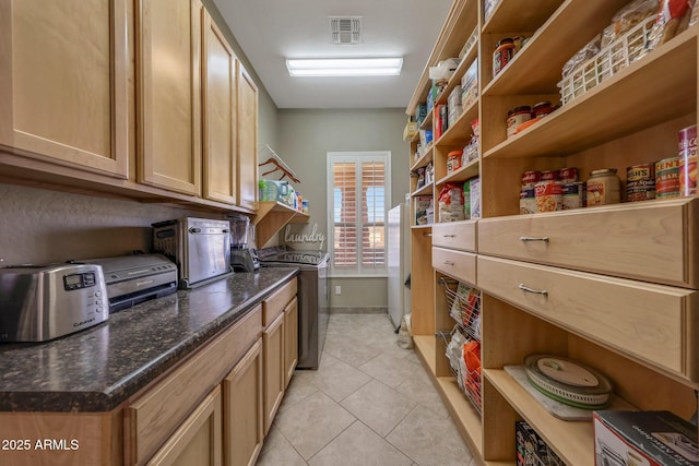 interior space with light tile patterned floors, baseboards, laundry area, and visible vents