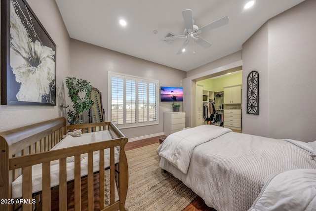 bedroom with baseboards, ceiling fan, wood finished floors, a walk in closet, and recessed lighting
