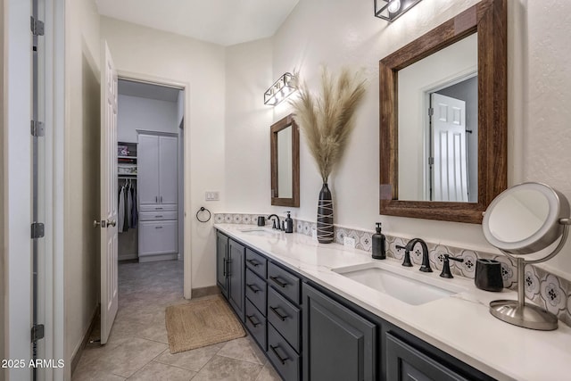 bathroom with tile patterned floors, a sink, a spacious closet, and double vanity