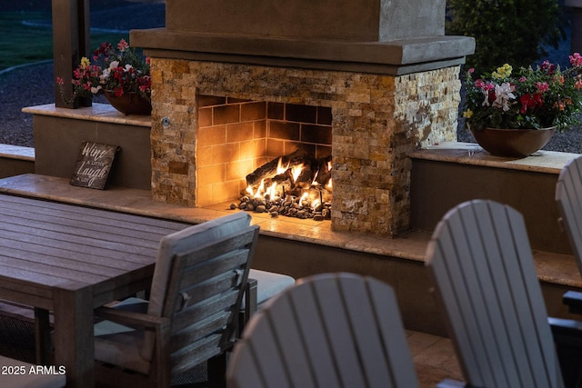 exterior space featuring stone siding and a warm lit fireplace