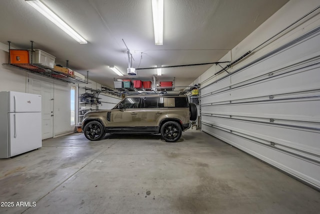garage with freestanding refrigerator and a garage door opener