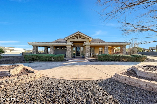 view of front of house with stone siding, a tiled roof, and stucco siding