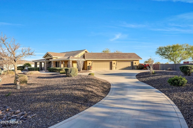 view of front of house with a garage, a tile roof, fence, driveway, and stucco siding