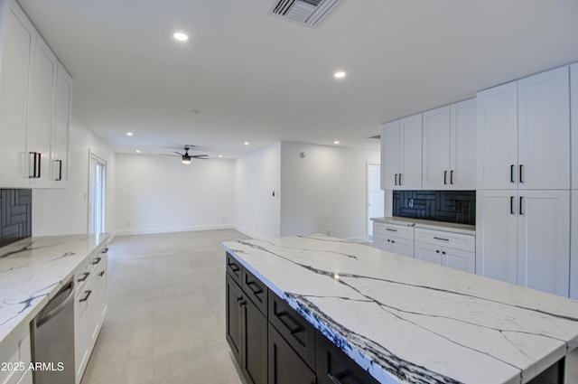 kitchen featuring a center island, stainless steel dishwasher, white cabinets, and backsplash