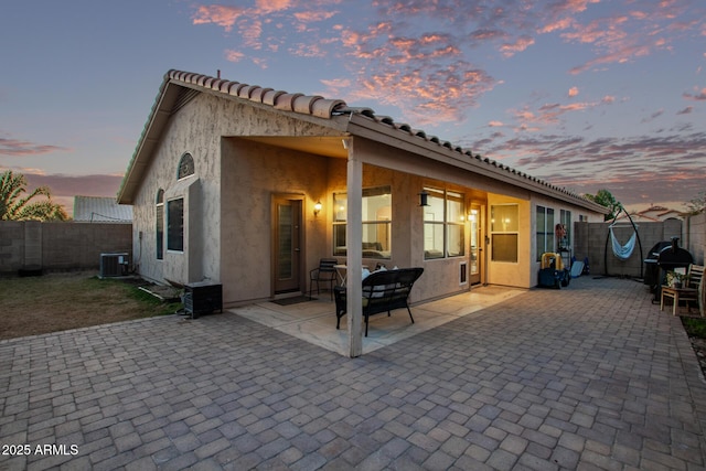 back house at dusk featuring a patio area and central air condition unit