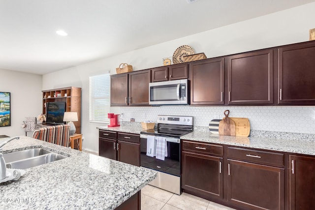 kitchen with sink, light stone countertops, appliances with stainless steel finishes, tasteful backsplash, and light tile patterned flooring