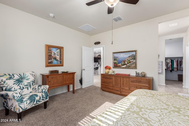 bedroom with ceiling fan, a walk in closet, light carpet, and a closet