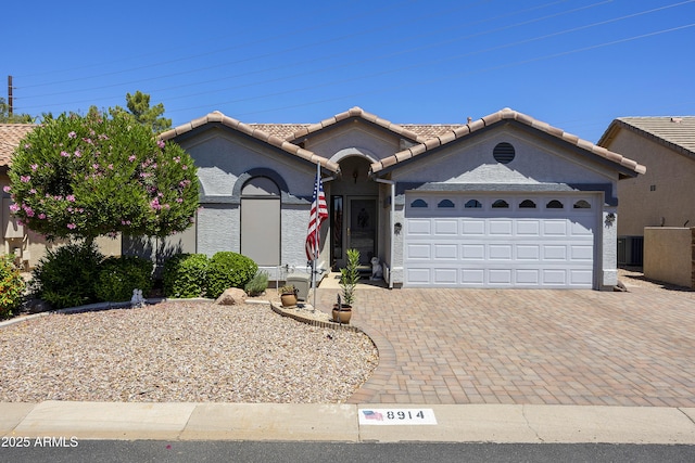 view of front of house featuring central AC, an attached garage, decorative driveway, a tile roof, and stucco siding