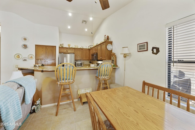 dining area featuring ceiling fan, light tile patterned floors, and high vaulted ceiling